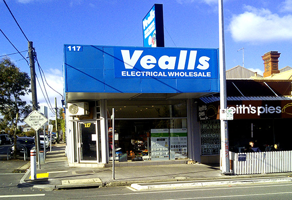 Vealls storefront with blue signage on the corner of two streets. Signage reads "Vealls Electrical Wholesale"
